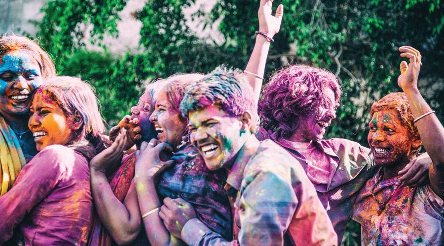 un grupo de jóvenes bañados en pintura y sonriendo en inglés