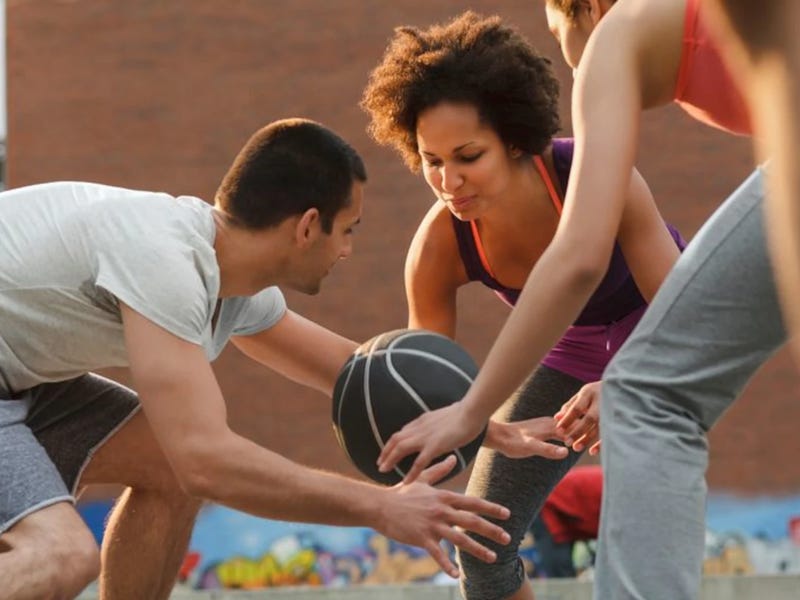 un grupo de adultos jóvenes jugando baloncesto