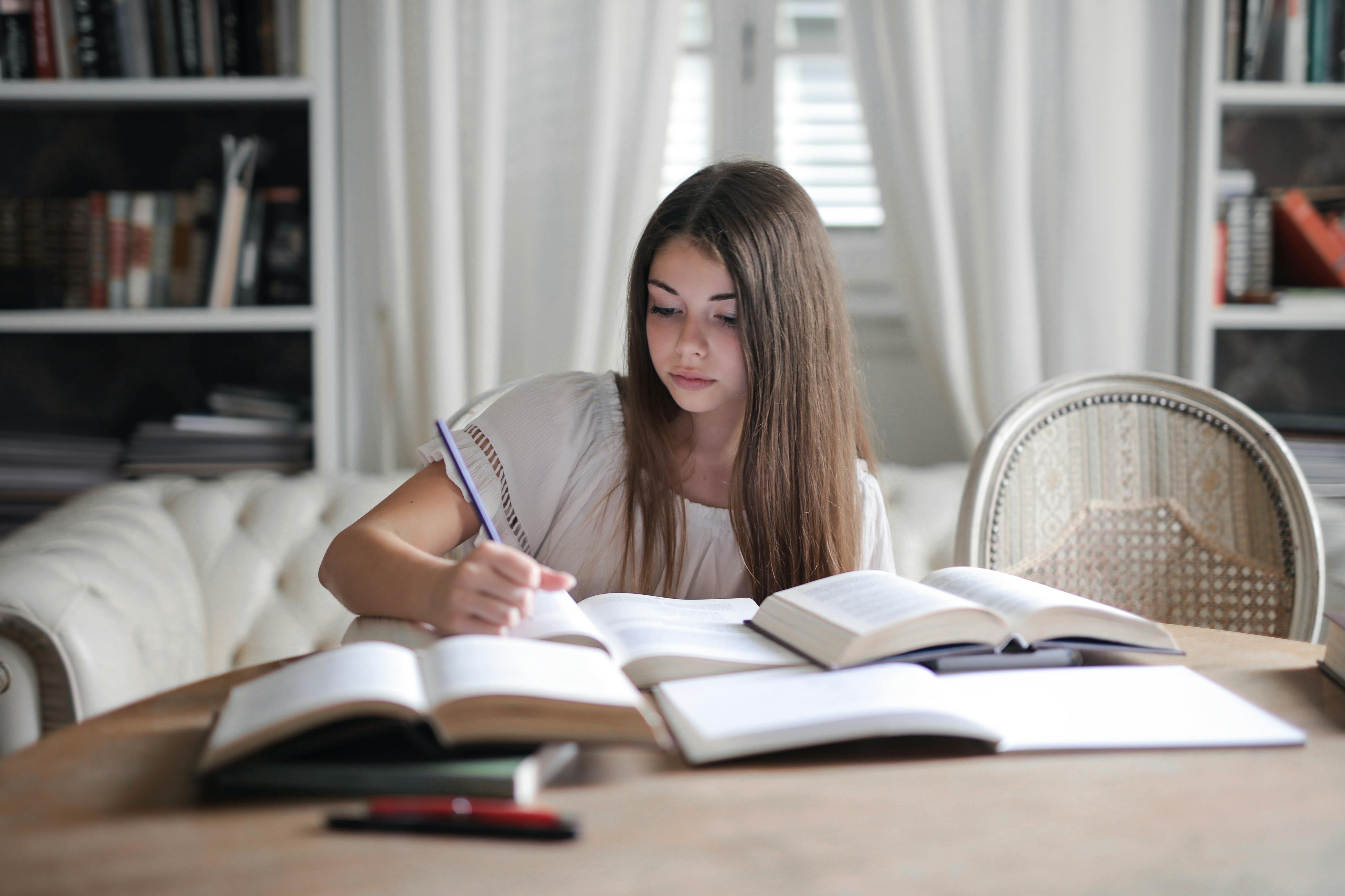 Chica estudiando con libros las opciones de expresiones de cortesía en inglés.