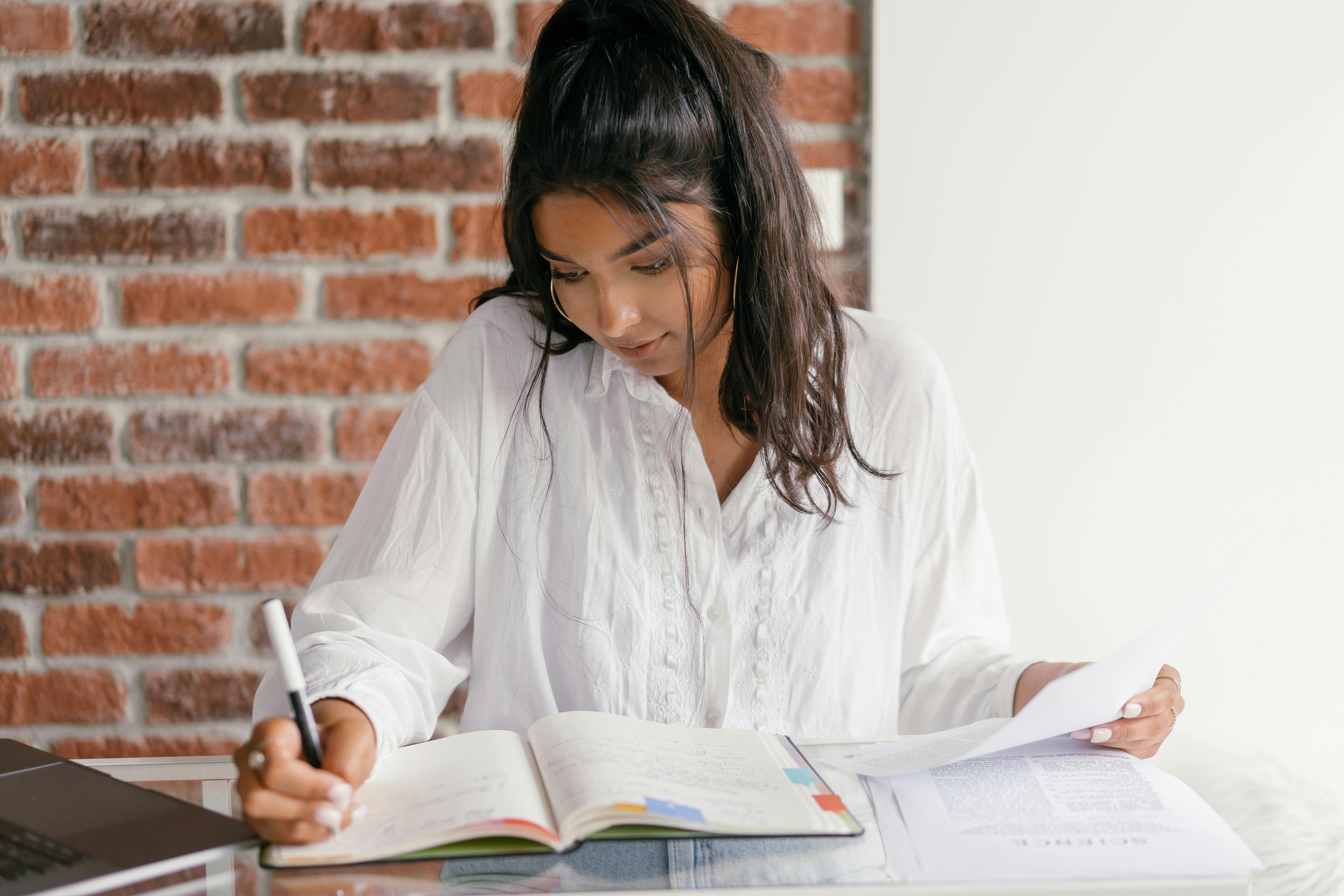 Mujer estudiando con su libro sobre verbos en portugués.