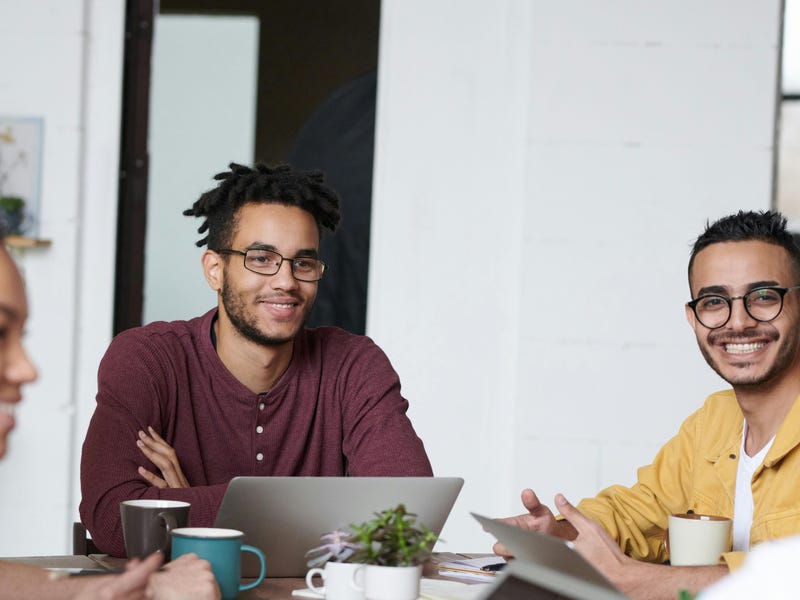 Varias personas sentadas en una mesa en una oficina, felices con el bilingüismo del quipo.