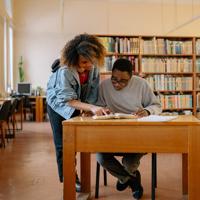 Dos jóvenes comparten un diccionario inglés - español en una sesión de aprendizaje de idiomas.