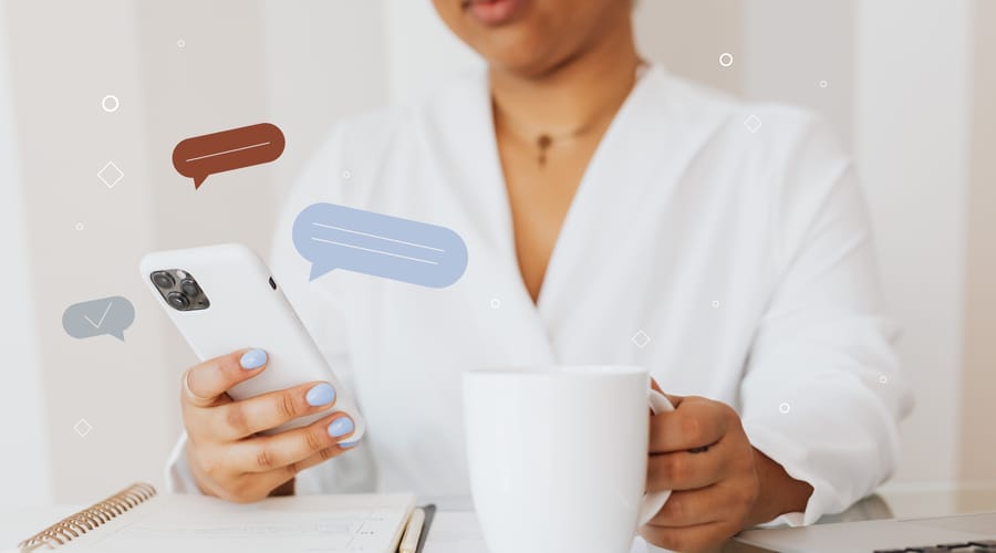 Una mujer con una taza blanca, viendo en su celular un artículo sobre reglas gramaticales nuevas.