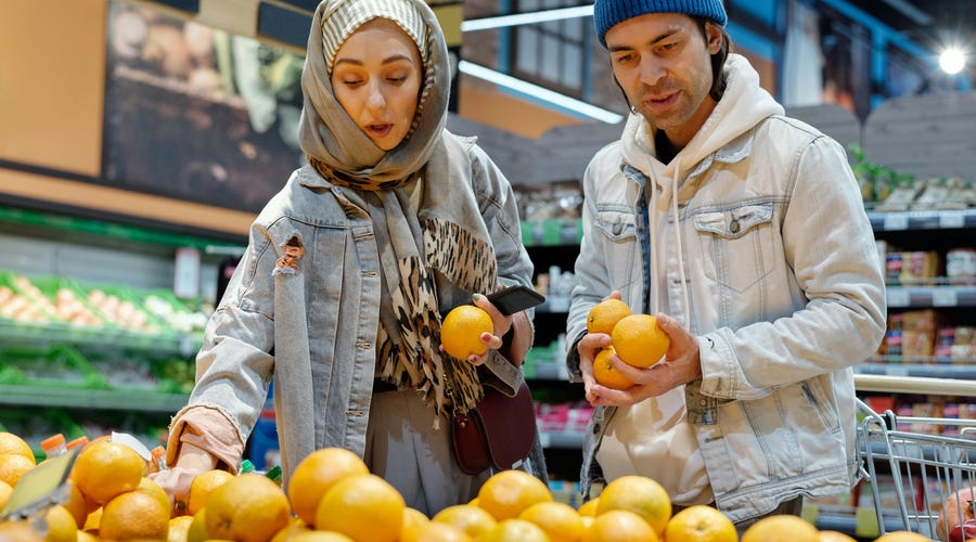 Pareja en el mercado buscando frutas.