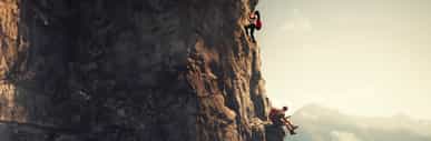 Two people climbing up the side of a cliff