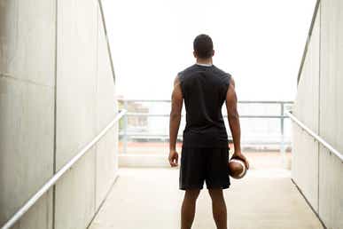 young athlete facing a field holding a football