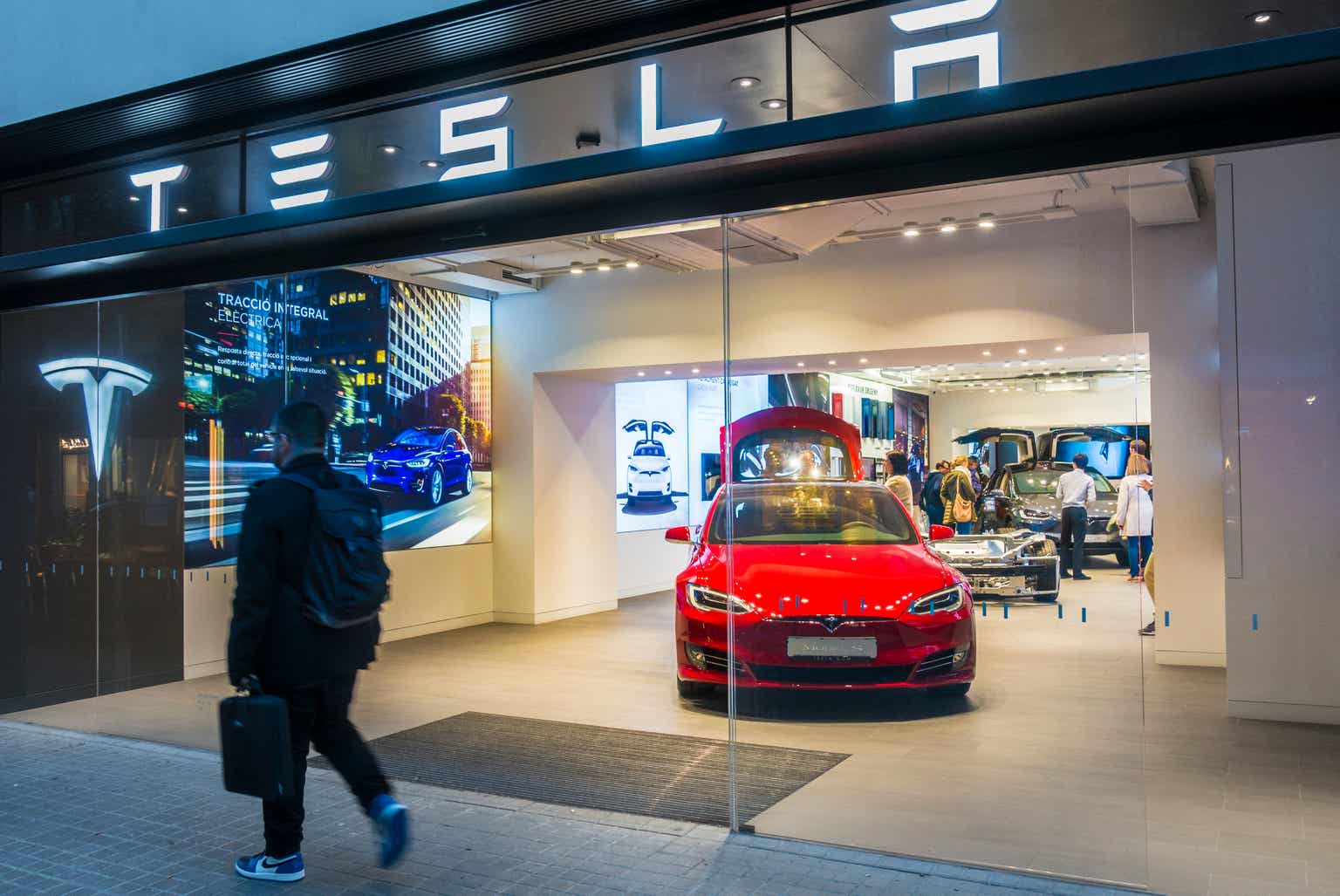 man walking in front of Tesla showroom