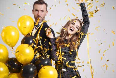 Two people celebrating with falling confetti and streamers