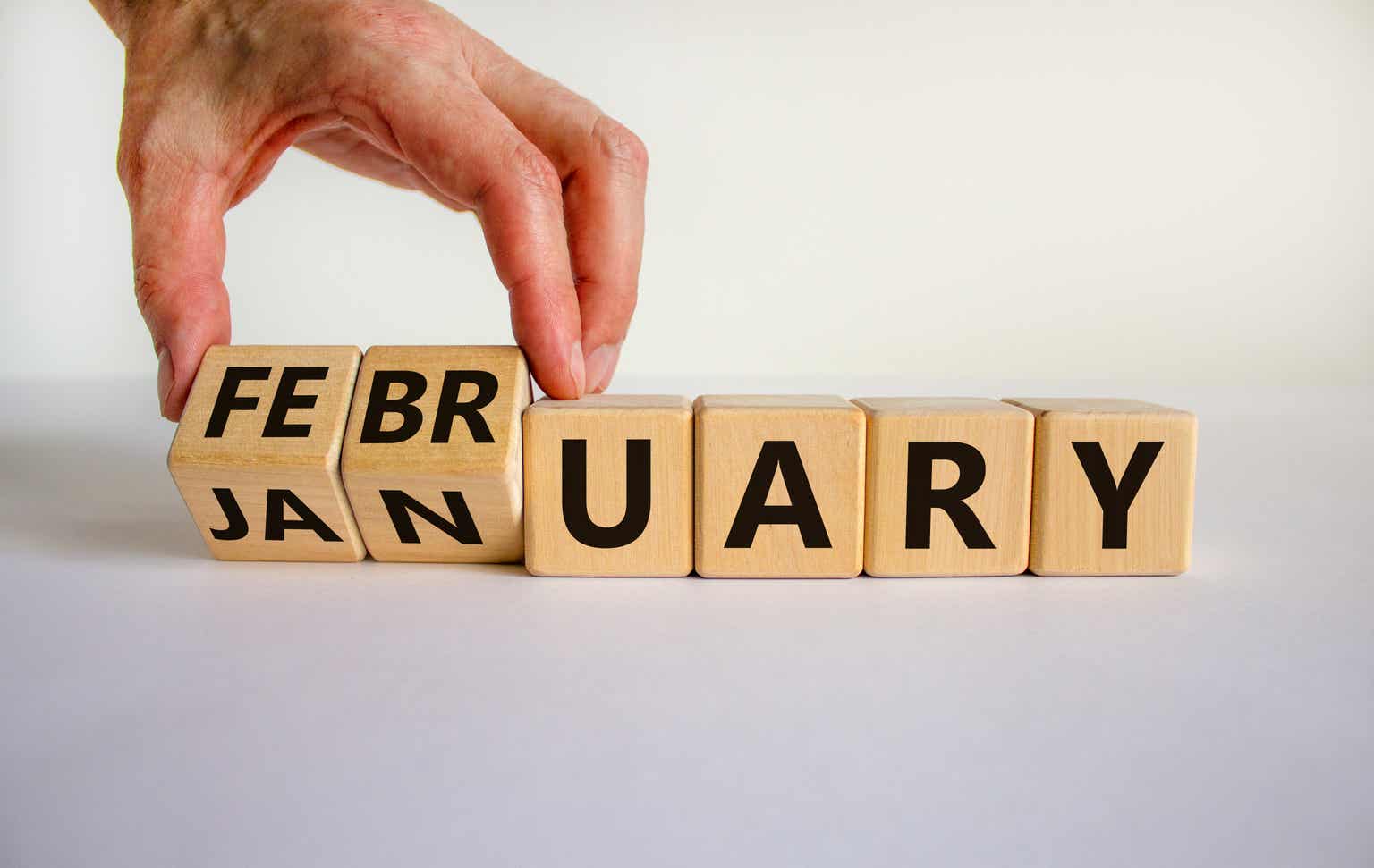 Hand moves wooden cubes and changes the letters from January to February.