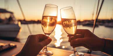 A close-up shot of friends clinking sparkling wine glasses at sunset on a yacht. Refreshing cocktail drinks. Summer outdoor parties and celebrations concepts