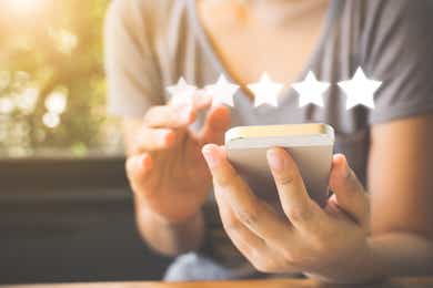 Person's hand using phone with five stars symbol above