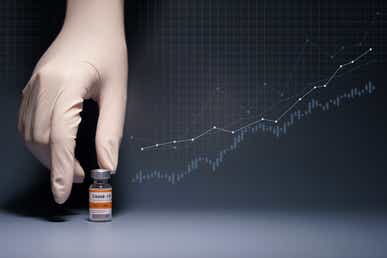 Hand with medical glove reaching for Pfizer vaccine with stock graph in the background