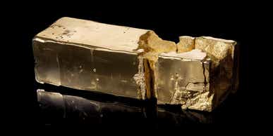 Made with midjourney: Solid gold bar split in half. One half shines brilliantly, reflecting light and exuding a sense of opulence. The other half is crumbling, dull, and lackluster, revealing a deteriorating texture. The contrasting halves represent the juxtaposition of solidity and decay