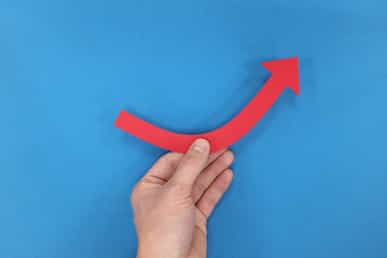 Hand holding upward arrow against blue background