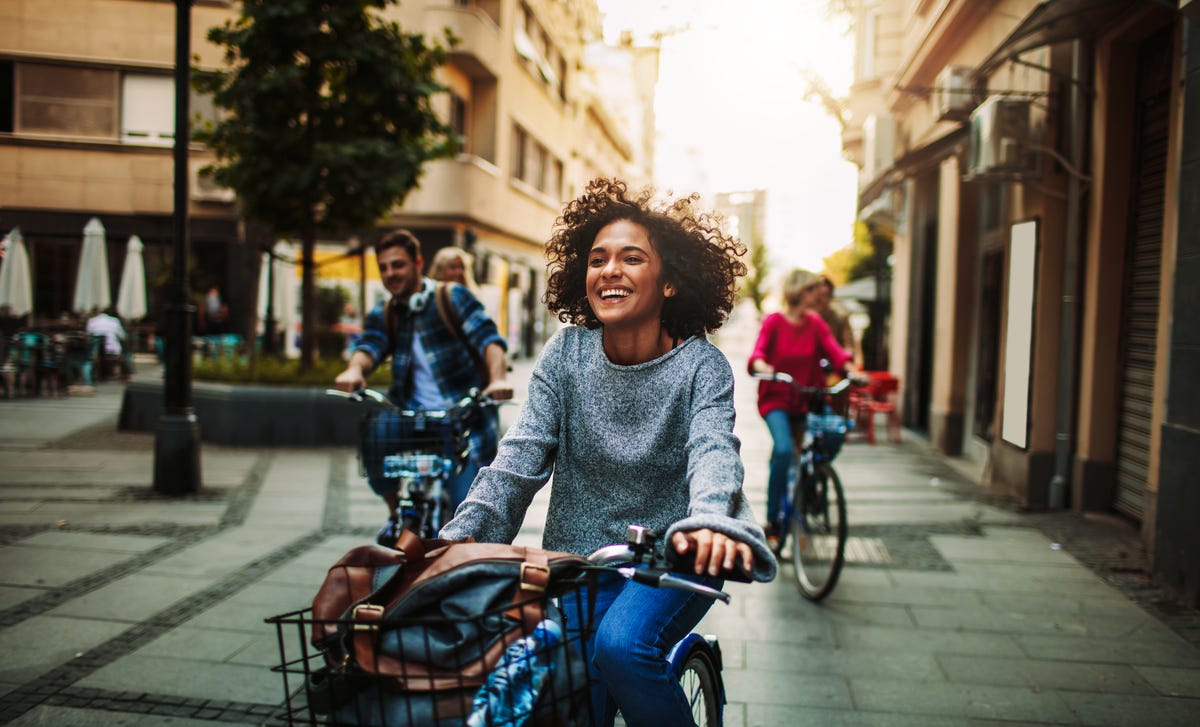 Joven sonriendo mientras anda en bicicleta por la ciudad