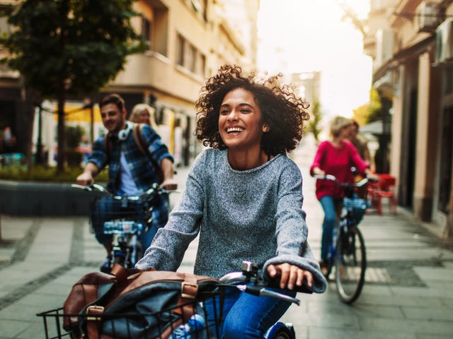 Joven sonriendo mientras anda en bicicleta por la ciudad