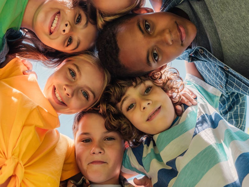 Grupo diverso de niños miran hacia abajo, sonriendo, campamento de idiomas Berlitz.