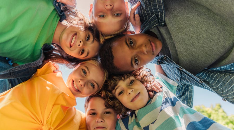 Grupo diverso de niños miran hacia abajo, sonriendo, campamento de idiomas Berlitz.