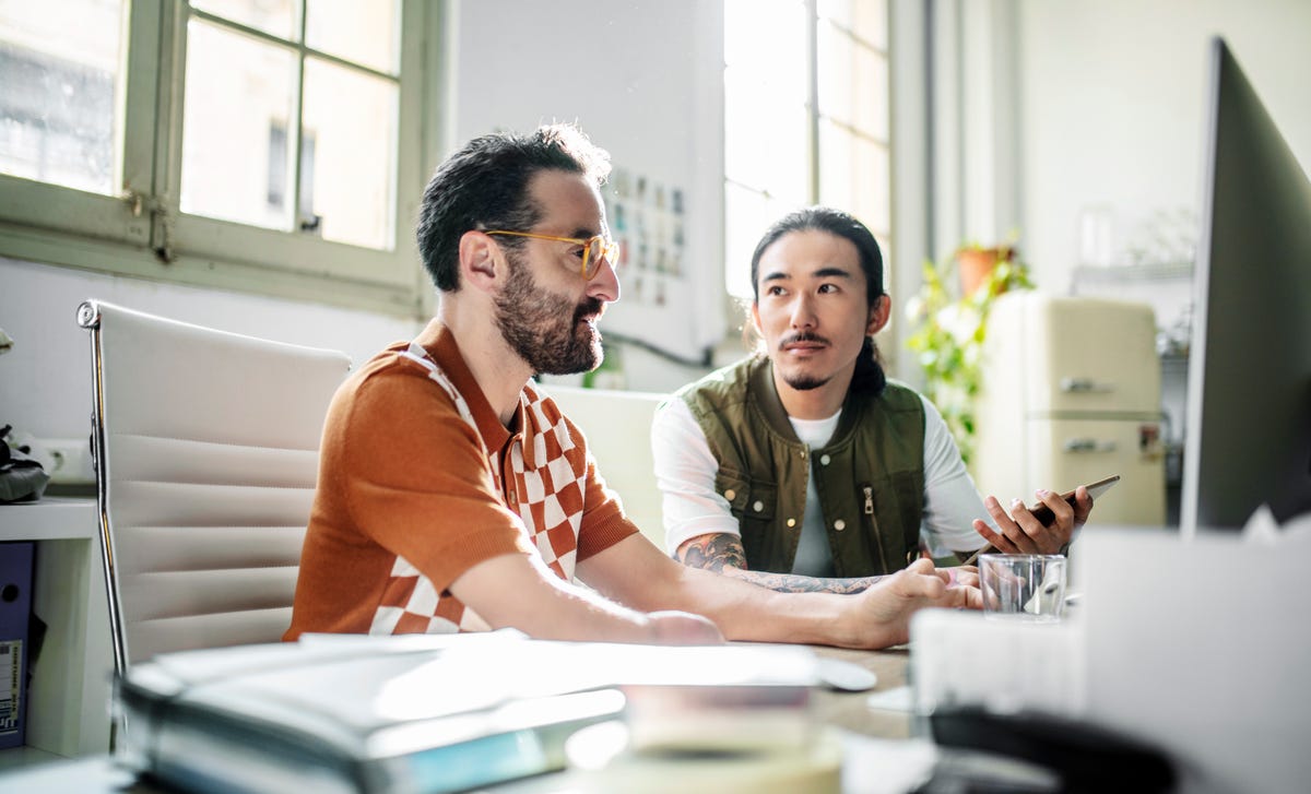 Dos colegas atentos conversan en una oficina moderna, compartiendo ideas.