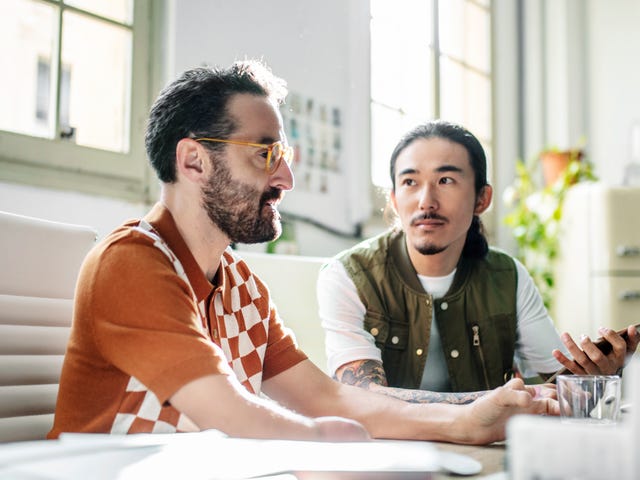 Dos colegas atentos conversan en una oficina moderna, compartiendo ideas.