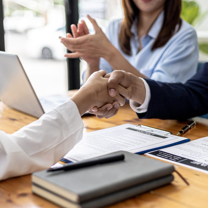 Personas en reunión de negocios estrechando manos, éxito profesional gracias a Berlitz.