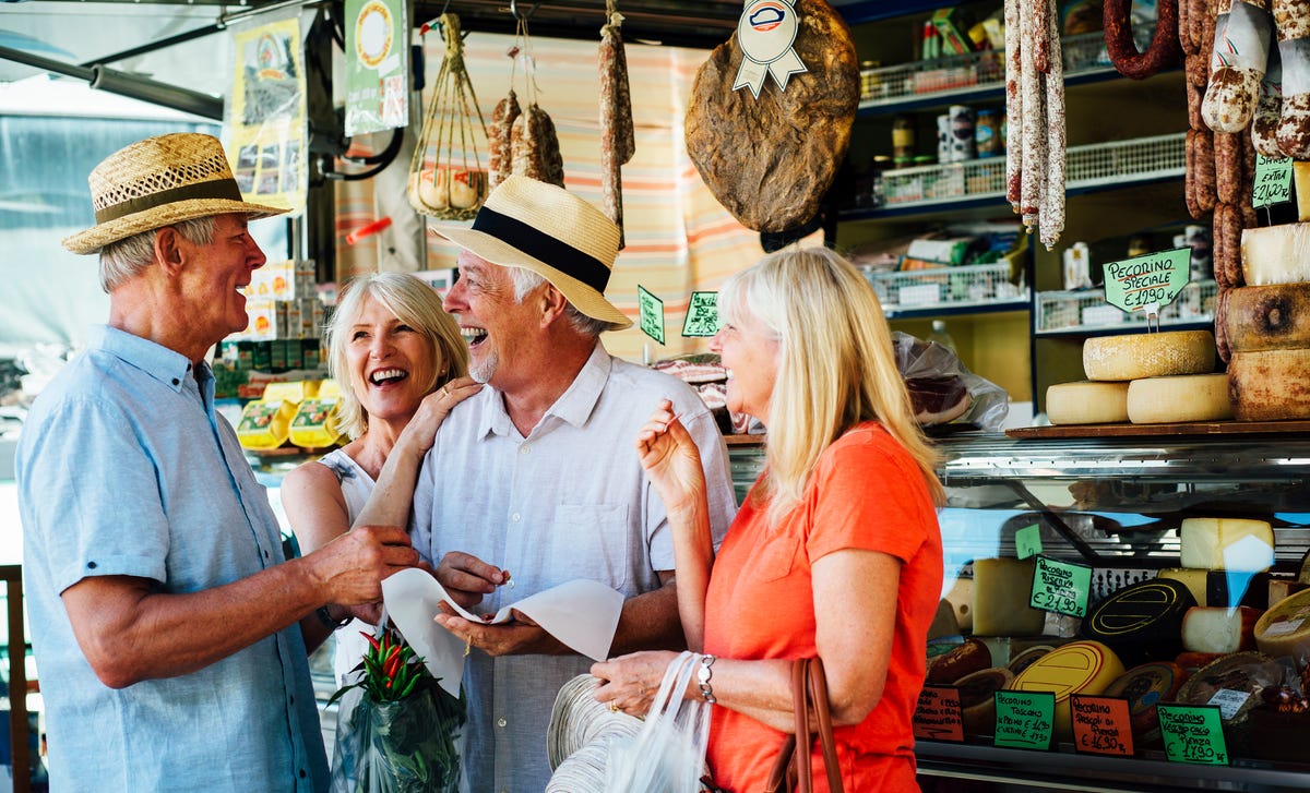 Amigos adultos mayores ríen y charlan mientras compran.