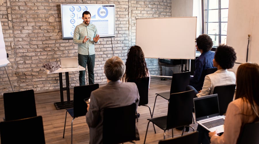 Profesional exponiendo gráficos de datos a una audiencia durante una capacitación de negocios.