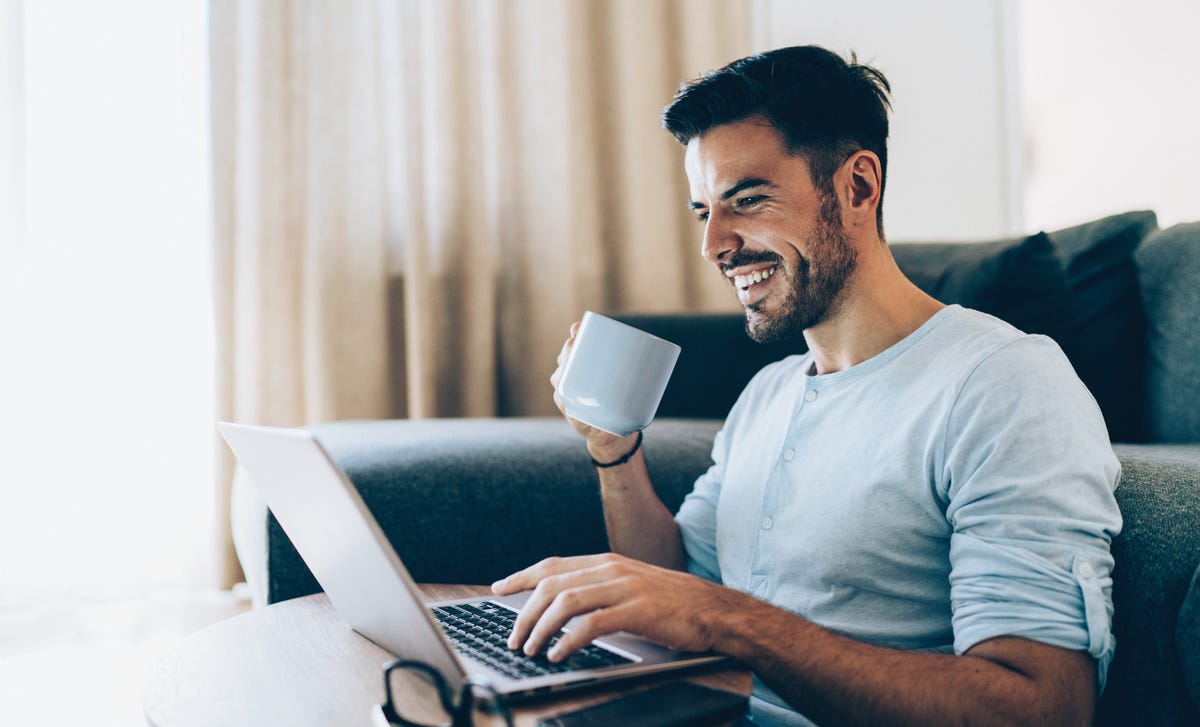 Estudiante de idiomas online Berlitz con café en laptop.