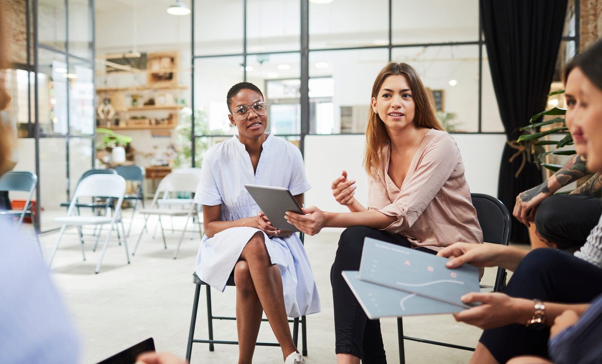 Dos mujeres explican algo con gestos en una reunión de grupo.