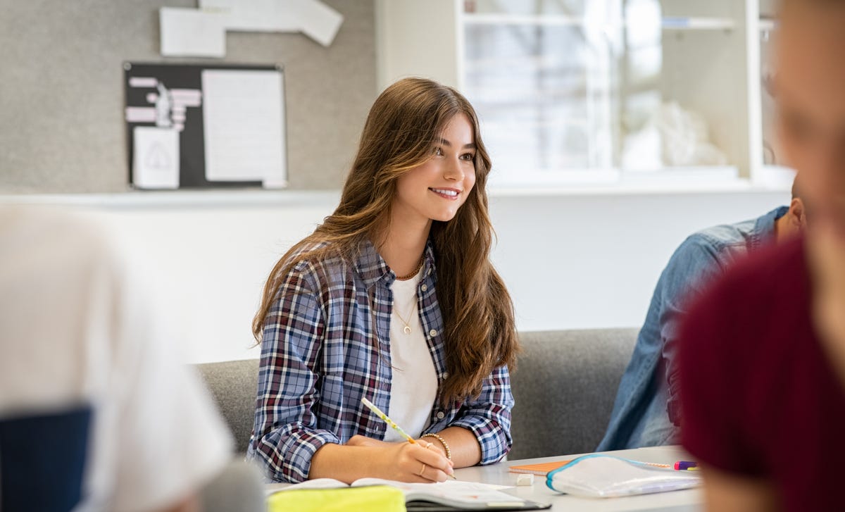Una joven estudiante atenta y participativa en una clase o sala de estudio.