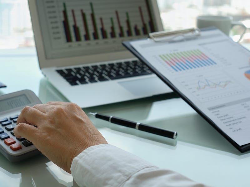 Manos trabajando con calculadora y gráficos de negocios, analizando finanzas.