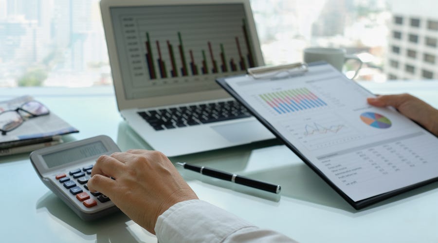 Manos trabajando con calculadora y gráficos de negocios, analizando finanzas.