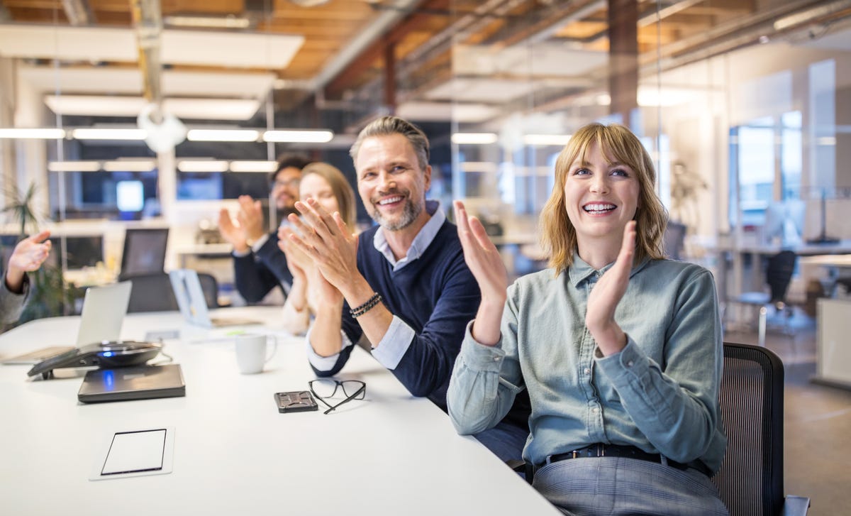 Personas de negocios aplaudiendo con entusiasmo en una reunión o presentación en la oficina.