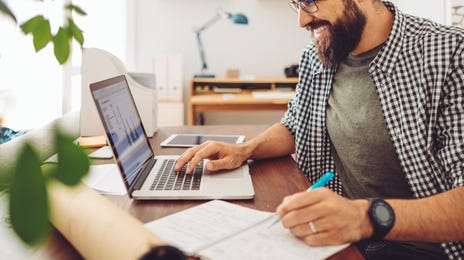Profesional sonriendo, estudia idiomas online Berlitz con laptop.