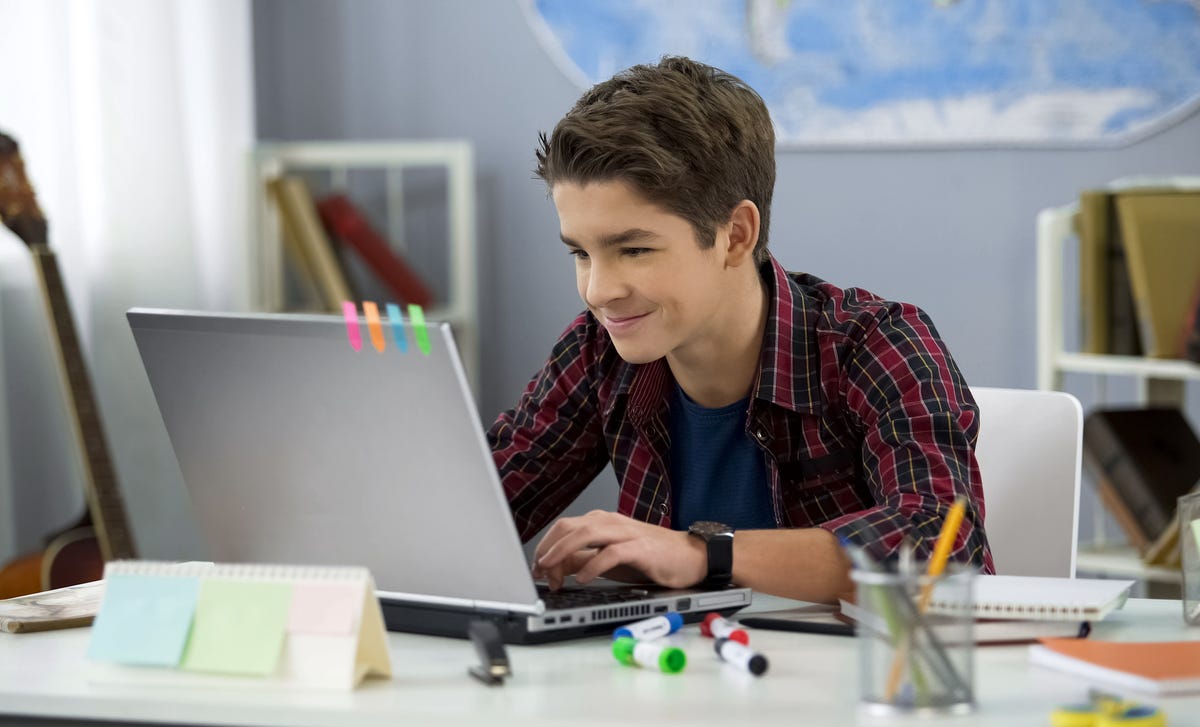 Un joven en su laptop, estudiando o entreteniéndose desde su hogar.