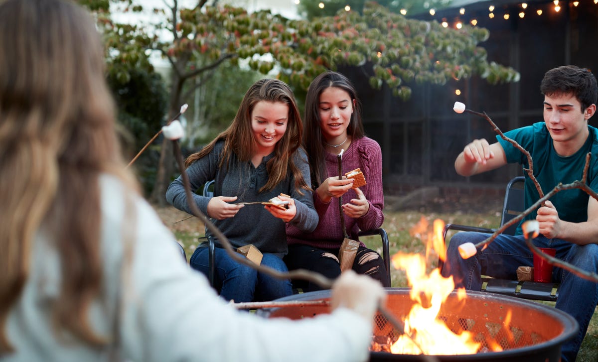 Adolescentes en un campamento, alrededor de una fogata en el patio.