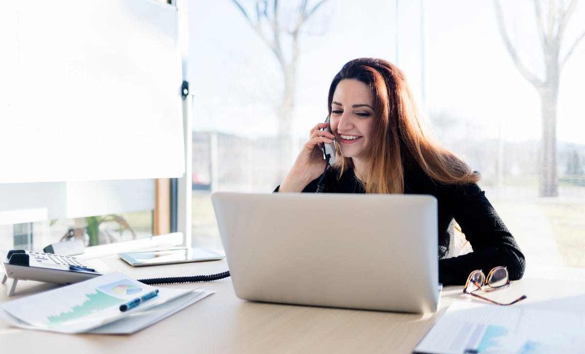 Una mujer de negocios sonriendo mientras habla por teléfono en su oficina.