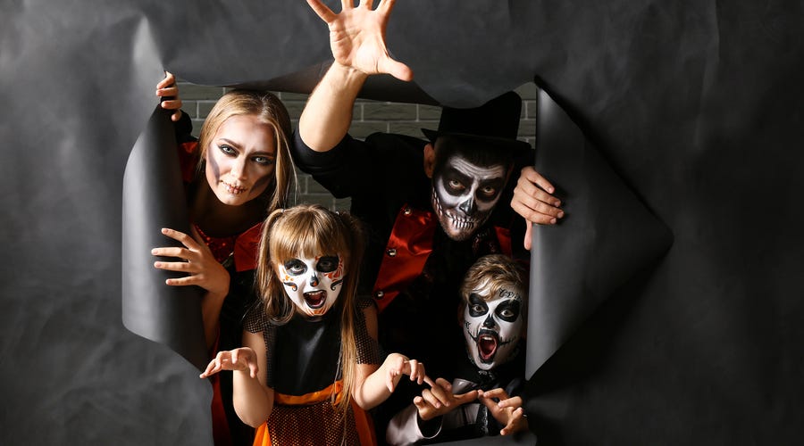 Familia disfrazada de esqueletos para Halloween, celebrando cultura y diversión con Berlitz.