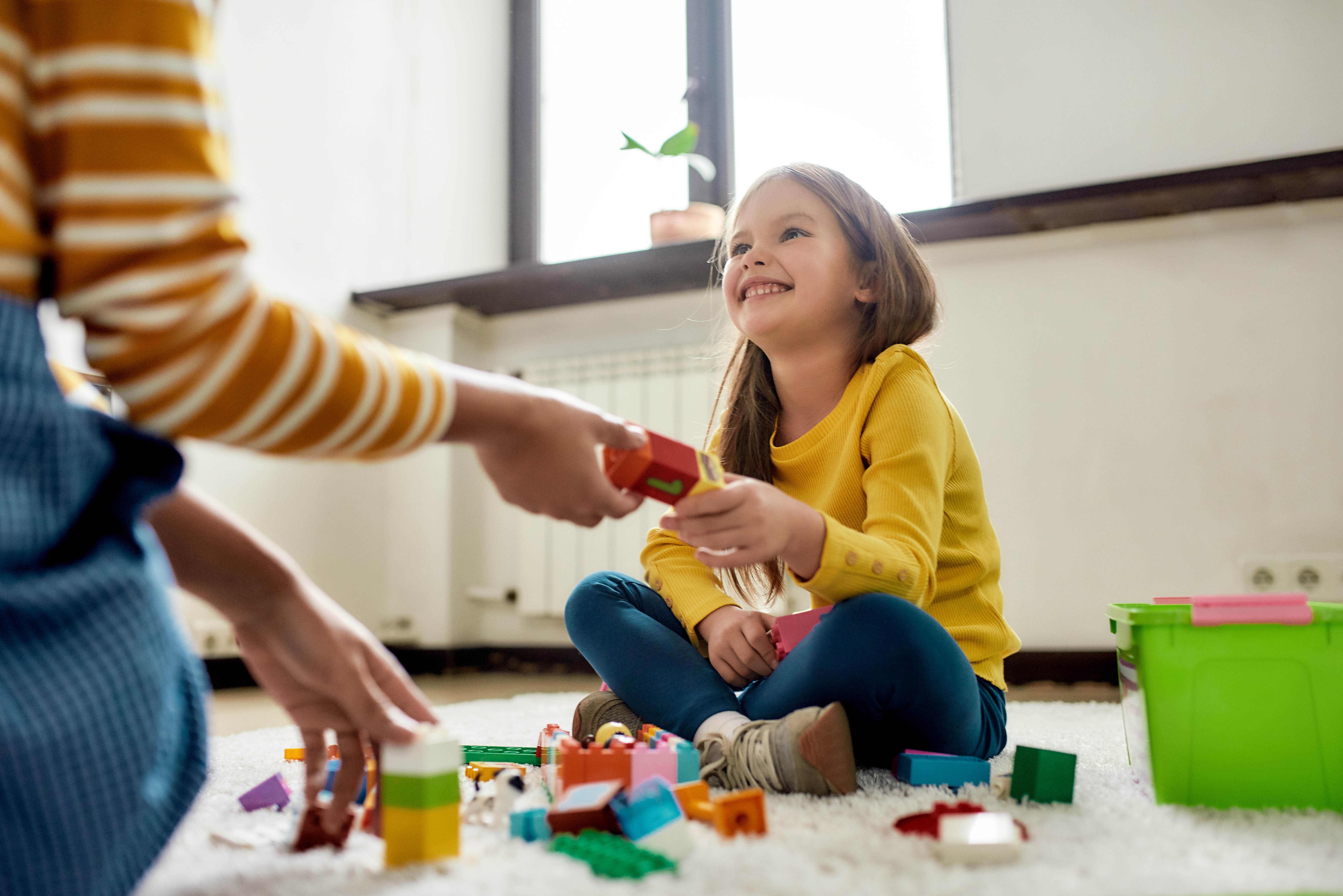 Niña sonriente jugando con bloques, aprendizaje infantil interactivo con Berlitz.