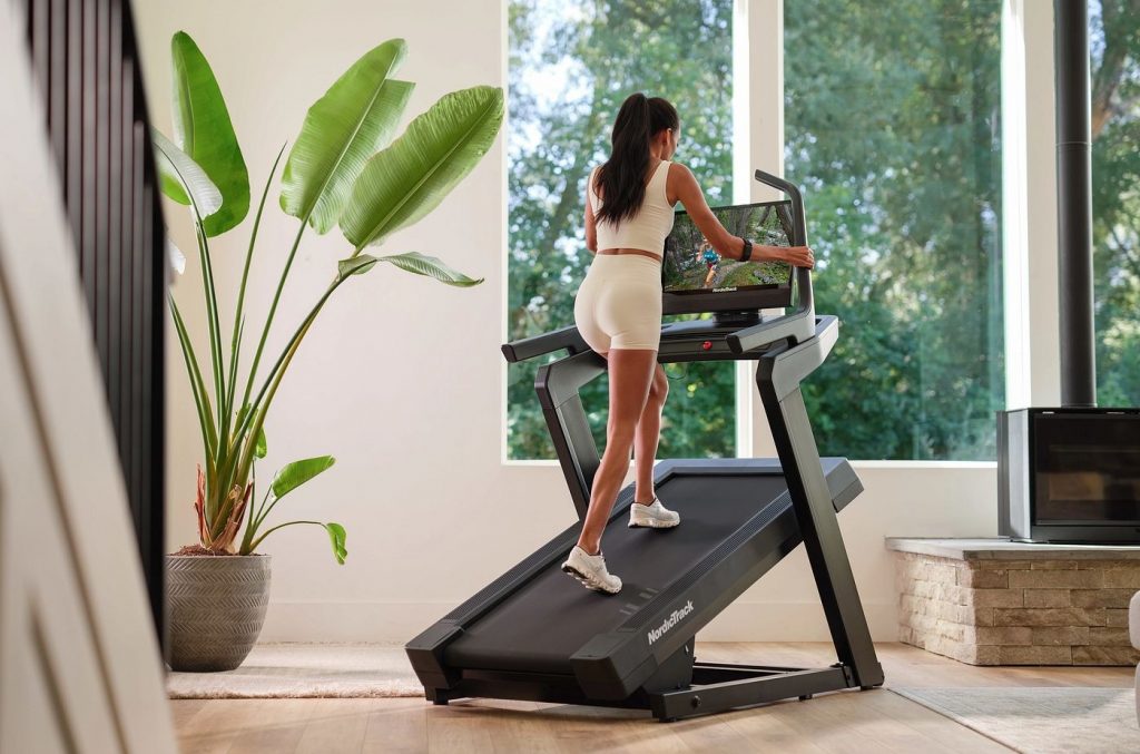 User walking at incline on a NordicTrack treadmill while following an iFIT workout, demonstrating structured, guided cardio training at home.
