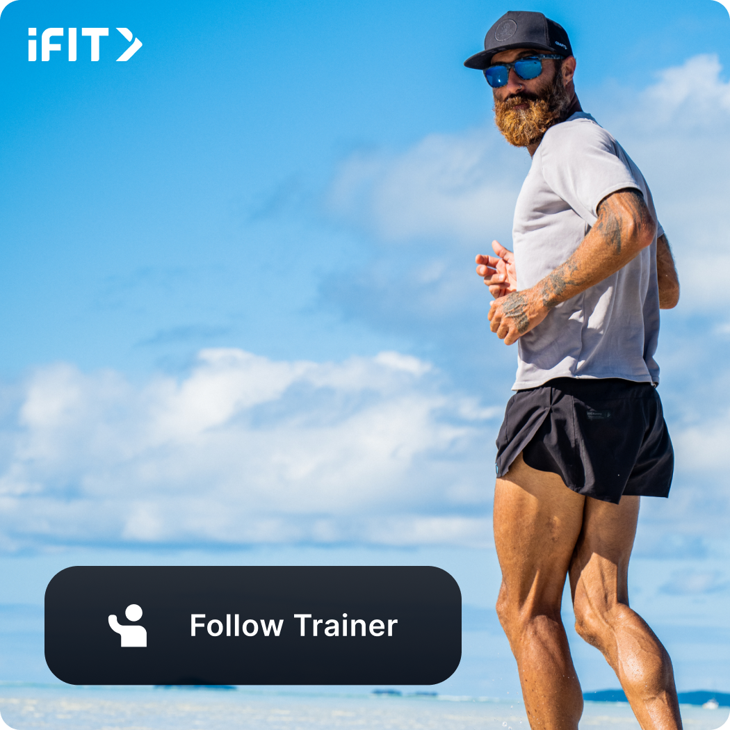 iFIT Trainer Tommy Rivs Puzey wearing sunglasses, a black hat, shorts, and a t-shirt looking back during a jog.