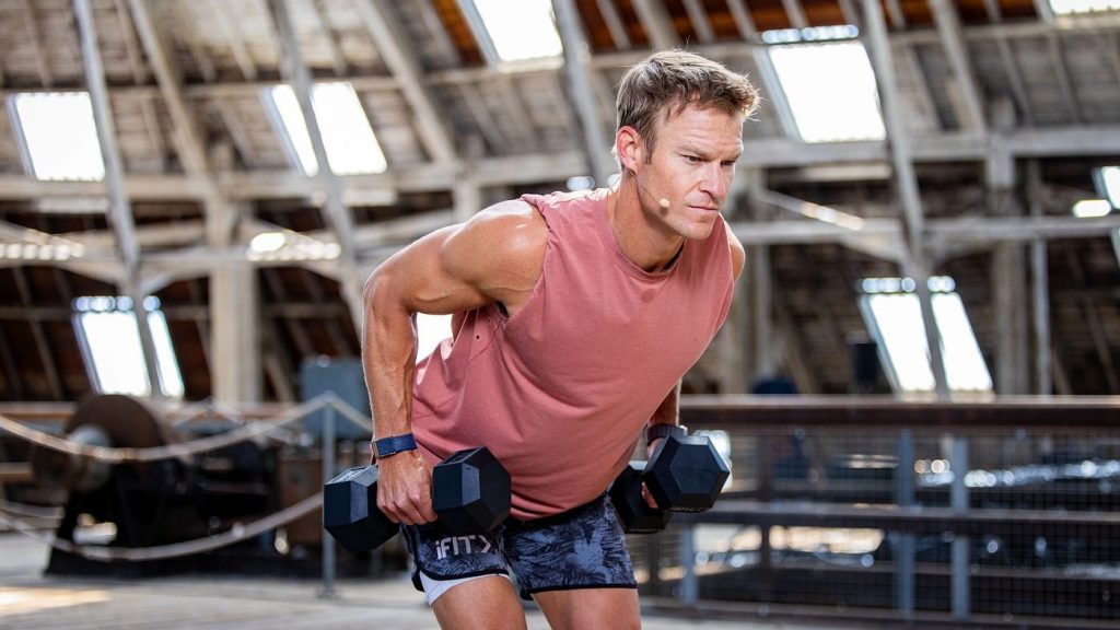 Trainer performing dumbbell rows during a structured strength workout, emphasizing controlled movement and muscle maintenance.