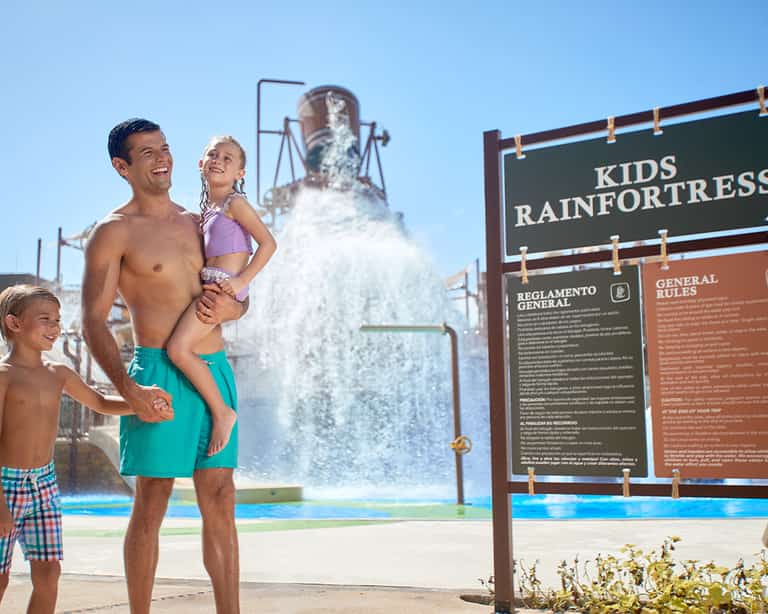 Familia junto al letrero de reglamento de Kids Rain Fortress en Jungala Aqua Experience