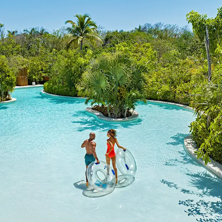 Pareja ingresando al río lento de Jungala Aqua Experience con donas inflables