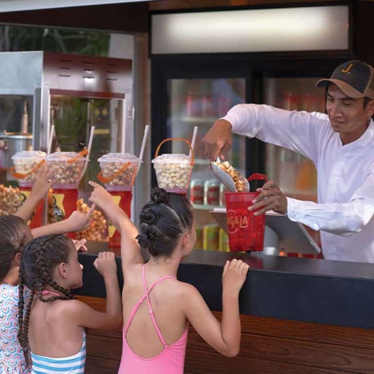 Estación de snacks de Jungala Aqua Experience, un empleado sirviendo palomitas a niñas