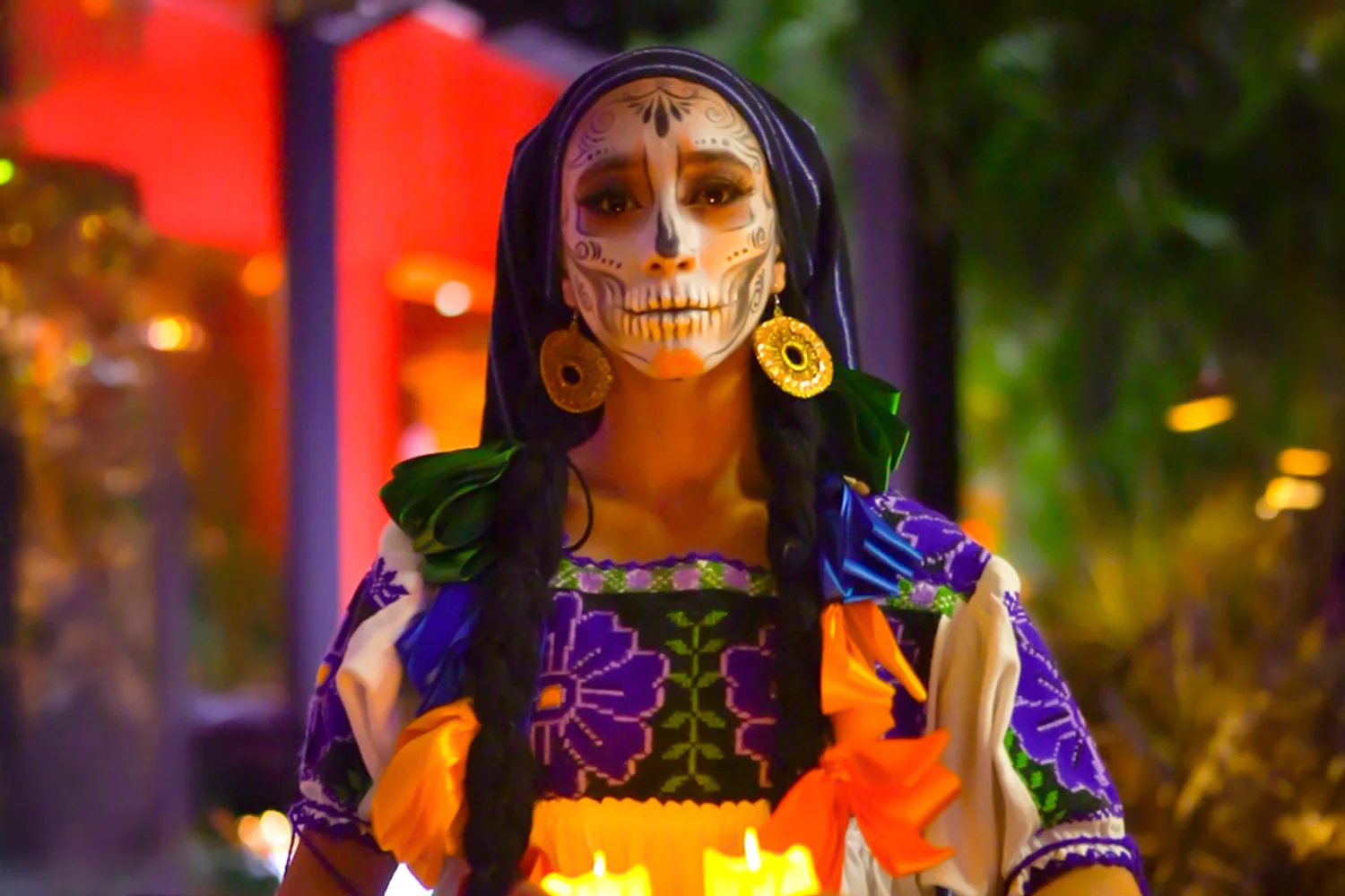 Catrina holding candles during the Día de Muertos procession