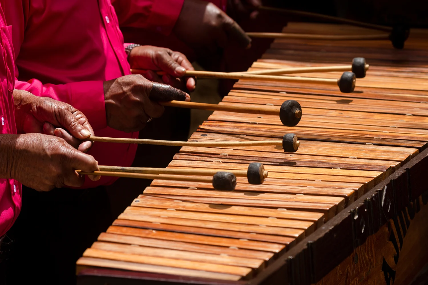 Hands playing a wooden marimba