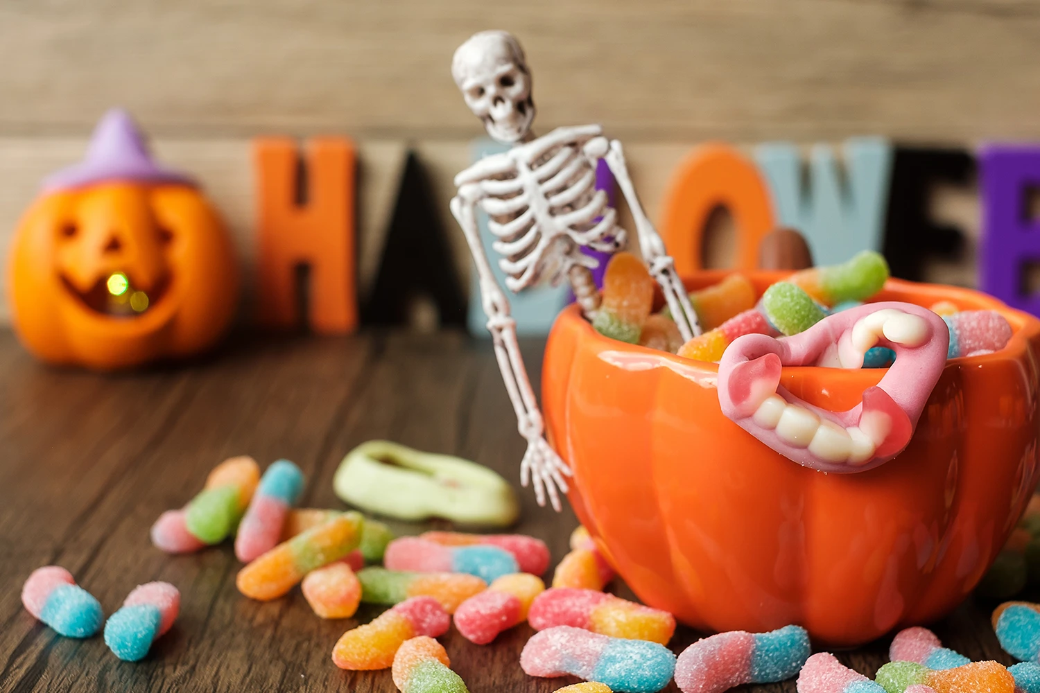 Skeleton sitting on a pumpkin bowl full of candy