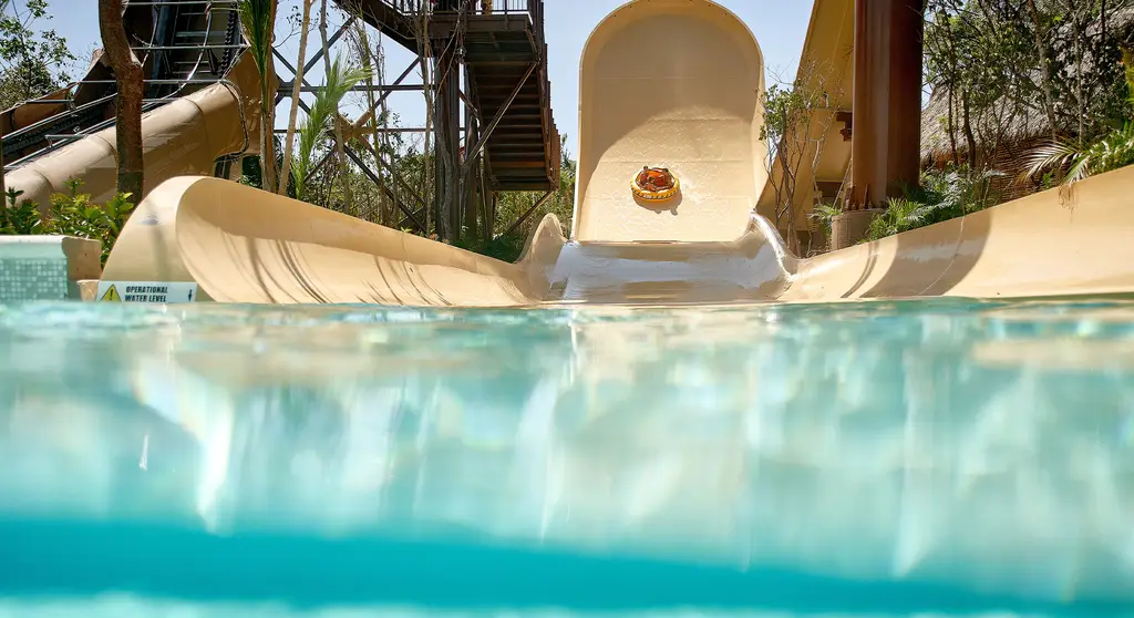 Vista a nivel del agua de un tobogán en Jungala Aqua Experience, con visitantes descendiendo en balsa inflable