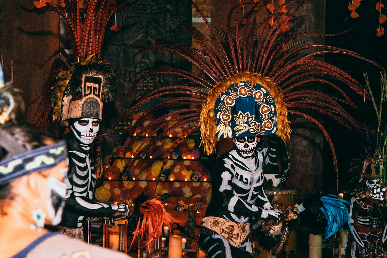 Performers in feathered headdresses and skeleton body paint